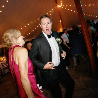 Man and woman dancing joyfully under string lights at elegant Bradley Estate wedding reception.