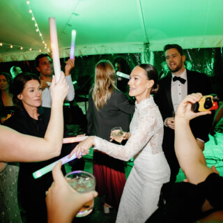 Bride dancing with guests under string lights at lively Bradley Estate wedding in Canton, MA.