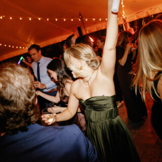Woman dancing joyfully under glowing string lights at Bradley Estate wedding in Canton, Massachusetts.