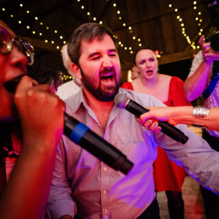 Guests singing and celebrating with joyful energy at a colorful Cunningham Farm wedding in Maine.
