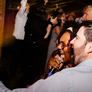 Wedding guests singing joyfully under warm lights at Cunningham Farm in New Gloucester, Maine.