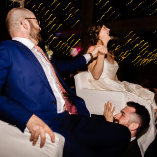 Bride and groom lifted during lively Jewish Hora dance at Cunningham Farm wedding celebration.