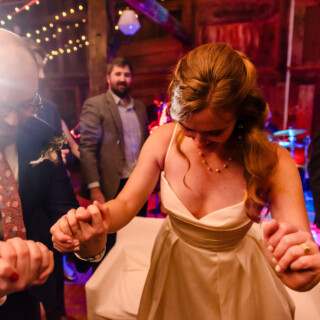 Bride and guests dancing joyfully at rustic barn wedding in New Gloucester, Maine.