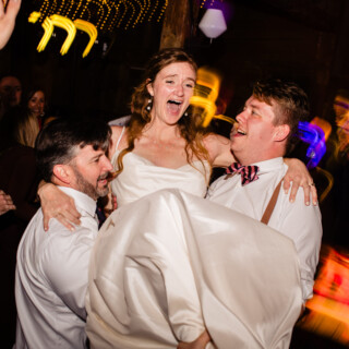 Bride lifted joyfully on dance floor during lively Cunningham Farm wedding celebration in Maine.