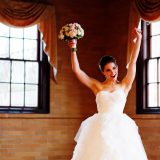 Joyful bride raising bouquet in celebration at Linden Place wedding in Bristol, Rhode Island.