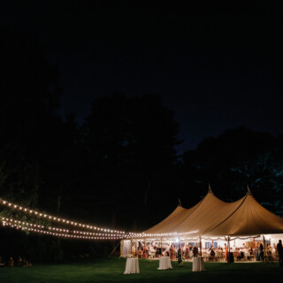 Romantic outdoor evening wedding under glowing tent lights at Moraine Farm in Beverly, MA.