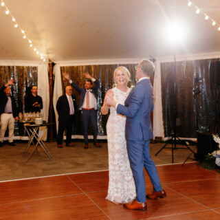 Bride and groom share a joyful first dance under glowing string lights at Moraine Farm wedding.