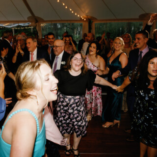 Guests dancing and laughing under string lights at a joyful Moraine Farm wedding celebration.