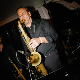 Jazz saxophonist performing passionately under warm stage lights at an intimate live event.