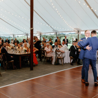 Two grooms share a joyful first dance under twinkling lights at Moraine Farm wedding.
