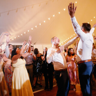 Guests dancing and celebrating under warm string lights at a joyful Moraine Farm wedding in Beverly.