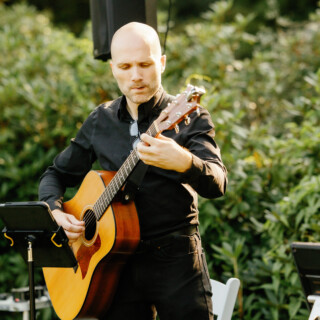 Bald guitarist performing live acoustic music at an elegant outdoor wedding in Beverly, Massachusetts.