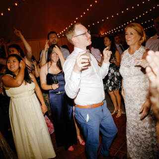 Guests dancing under string lights at a joyful Moraine Farm wedding reception in Beverly, Massachusetts.