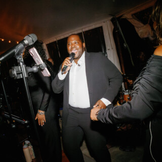 Joyful wedding singer performing under warm lights at Moraine Farm reception in Beverly, Massachusetts.