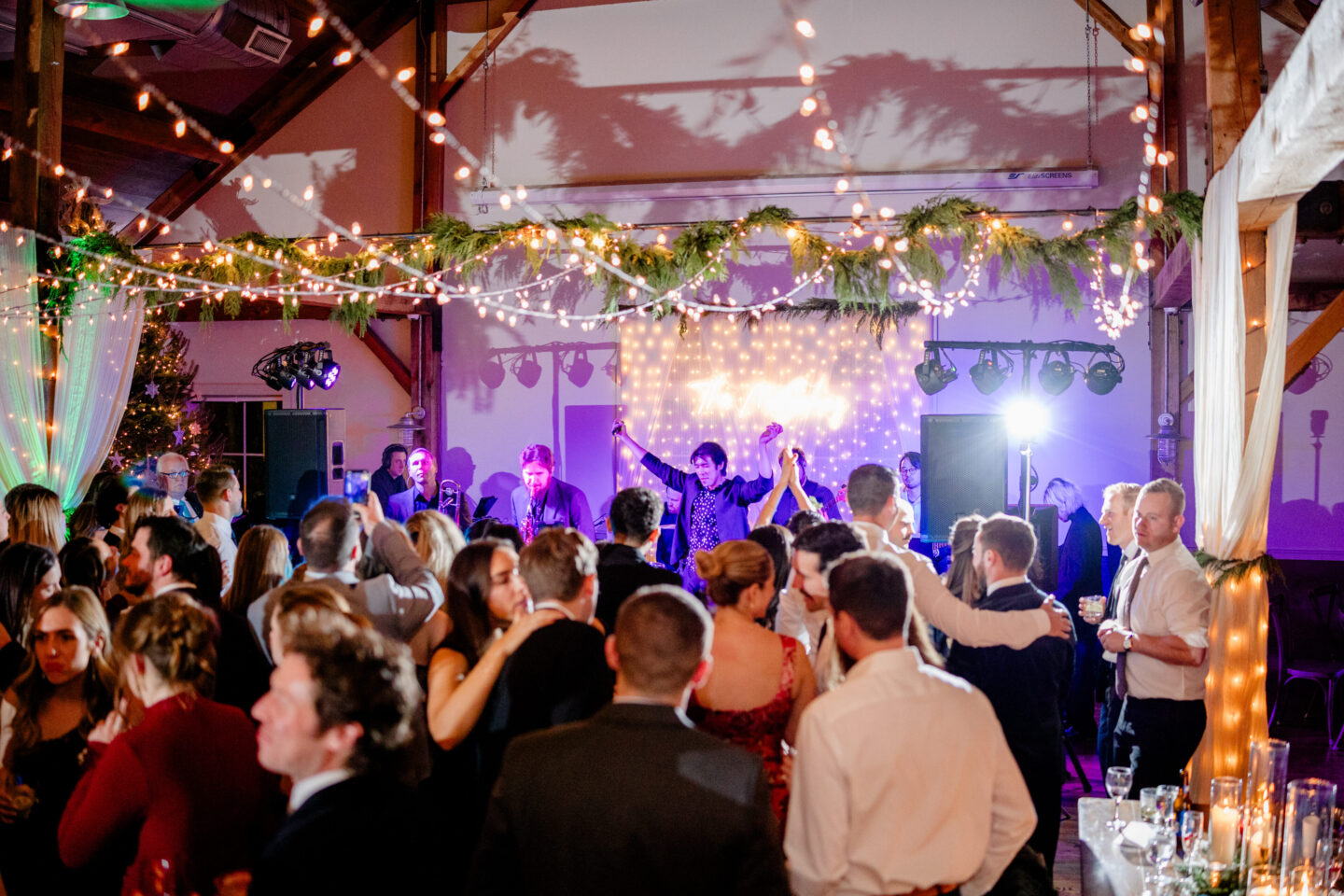 Bride and groom kiss under snowy evergreen arch at Mountain Top Inn winter wedding in Vermont.