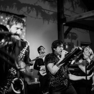 Black and white live band performance with passionate singers and musicians at an intimate venue.