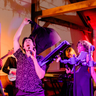 Energetic live band performance with passionate lead singer at intimate indoor venue.