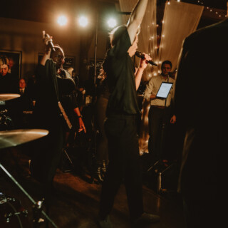 Live band performing at cozy indoor wedding reception with warm lights and joyful atmosphere.