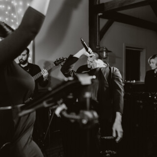 Black and white photo of passionate live band performance at rustic indoor wedding venue.