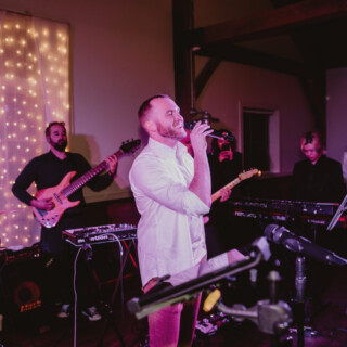 Live band performing at cozy indoor wedding reception with warm lights and rustic charm.