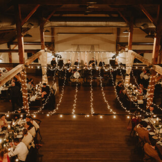 Rustic wedding reception with guests dining under warm fairy lights and live band performance.