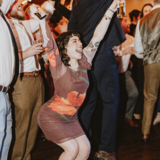 Guests dancing joyfully under warm string lights at a rustic Vermont wedding reception.