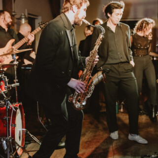 Live jazz band performing at an indoor wedding reception with passionate saxophonist and warm lighting.
