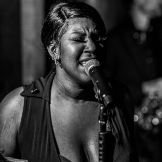 Black and white photo of soulful female singer performing passionately on stage.