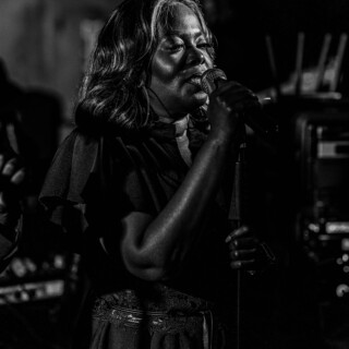 Black and white portrait of a soulful female singer performing passionately on stage.