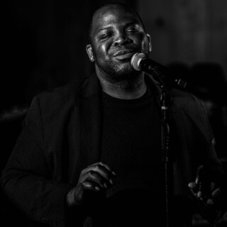 Emotional black-and-white portrait of a man singing passionately into a microphone.