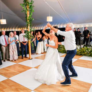 Bride and father dancing joyfully under glowing lights at Trapp Family Lodge wedding in Vermont.