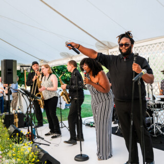 Live band performing under white tent at outdoor wedding reception in Stowe, Vermont.