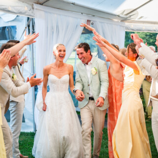 Bride and groom celebrating under white tent at Trapp Family Lodge wedding in Stowe, Vermont.