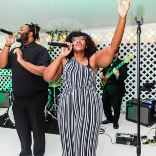 Energetic live band performing at Vermont wedding reception under elegant white tent.