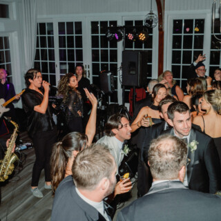 Guests dancing and celebrating as a live band performs at an elegant wedding reception.