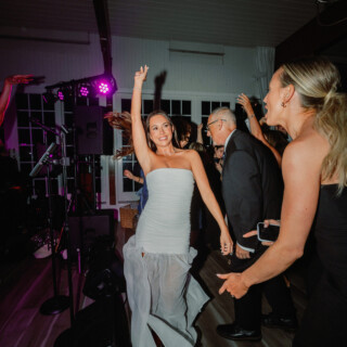 Bride dancing joyfully with guests under purple lights at Wychmere Beach Club wedding in Harwich.