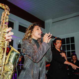 Female singer and live band performing under colorful lights at an elegant indoor event.